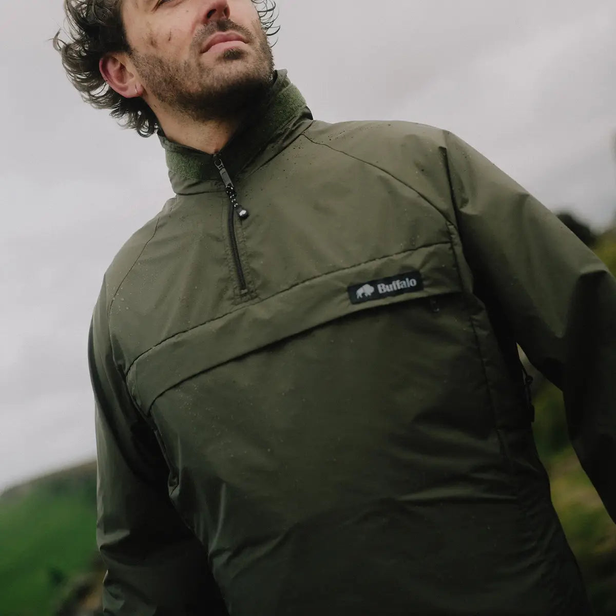 Close-up of man in olive green Buffalo Systems Special 6 Shirt by John Bull Clothing, highlighting durable Pertex fabric and chest branding.