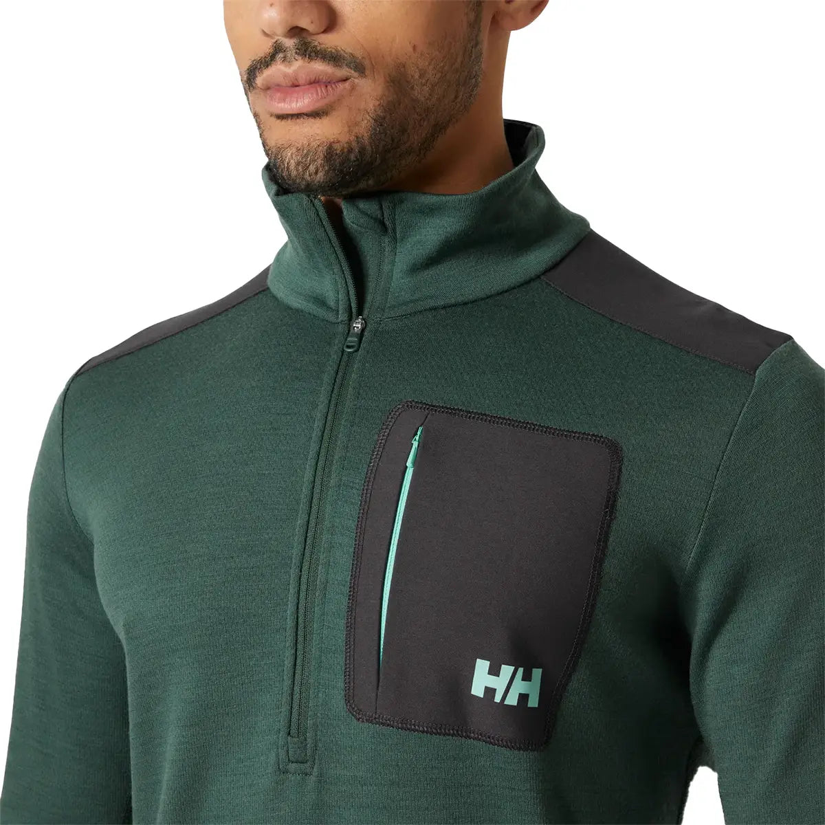 Close-up of Helly Hansen Lifa Merino Wool Mid Layer 1/2 Zip chest pocket with HH logo and contrast zipper, highlighting functional outdoor design.
