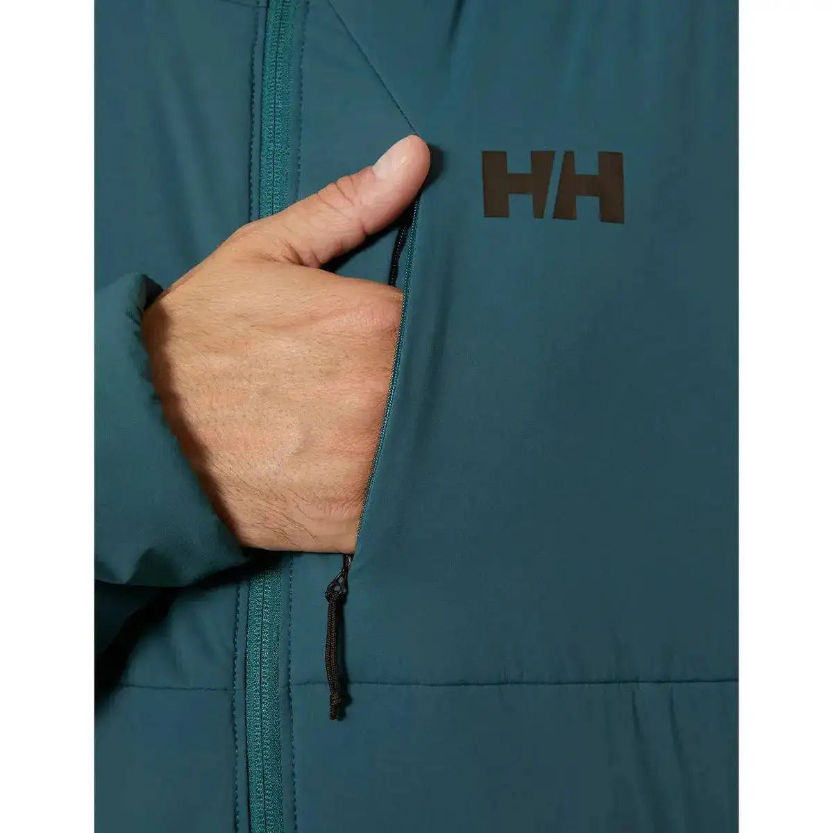 Zippered chest pocket of the Helly Hansen Odin Stretch Hood Insulator 2.0 Jacket, providing secure storage with a sleek design and HH logo branding.  from  John Bull Clothing 