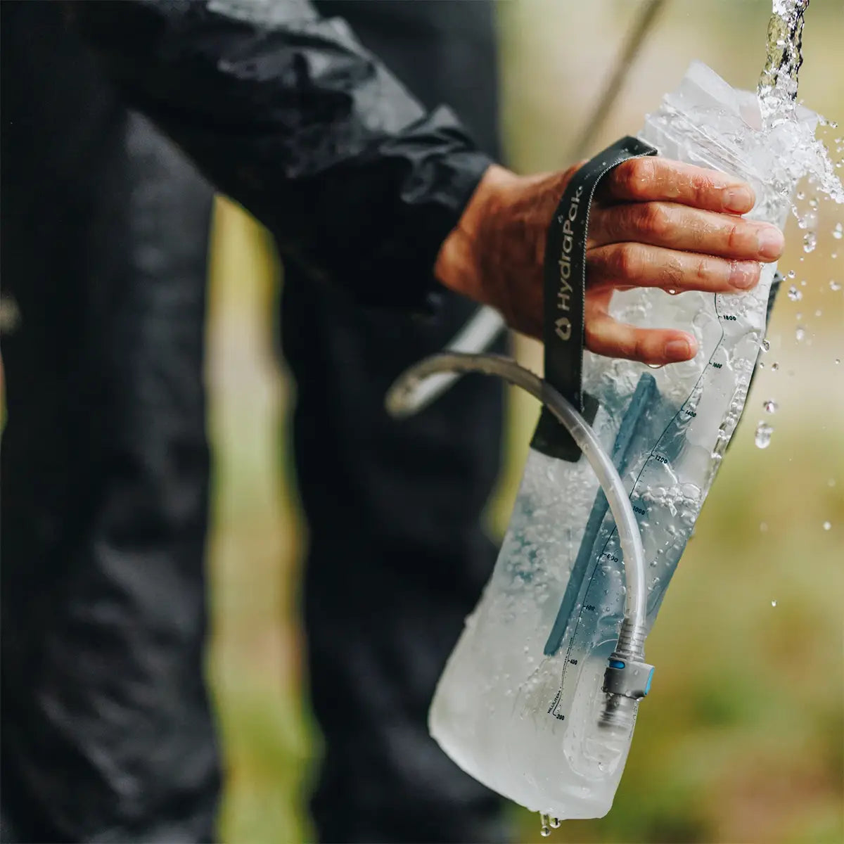 HydraPak Force Tactical Grey Water Reservoir in use outdoors, demonstrating its durability and leak-proof performance in wet conditions.