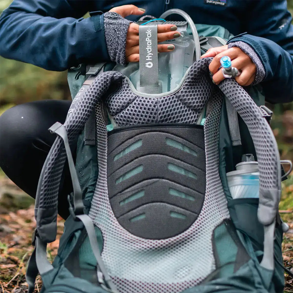HydraPak Contour Clear Water Reservoir being inserted into a backpack, highlighting its ergonomic fit and hydration tube accessibility.  from  John Bull Clothing 