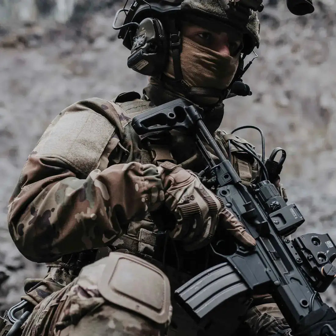 Operator wearing MoG Target High Abrasion Ergoshield Gloves in Multicam while holding a rifle, showcasing tactical performance in combat-ready environments.  from  John Bull Clothing 