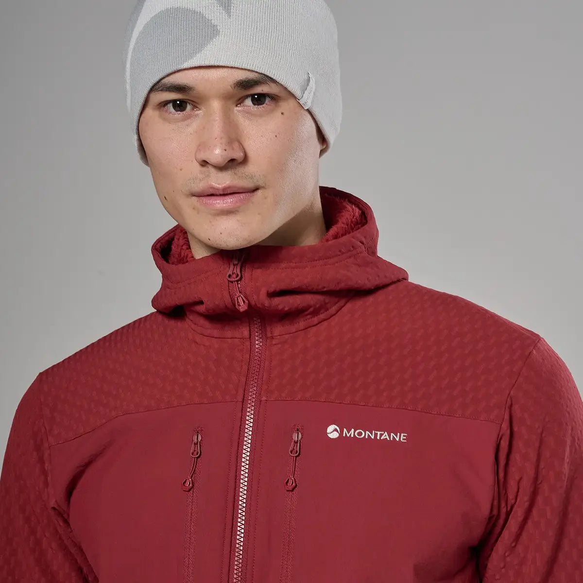 Close-up of male model wearing red Montane Mens Dura XT Hoodie fleece with hood, front zipper, and logo, suitable for cold weather outdoor adventures