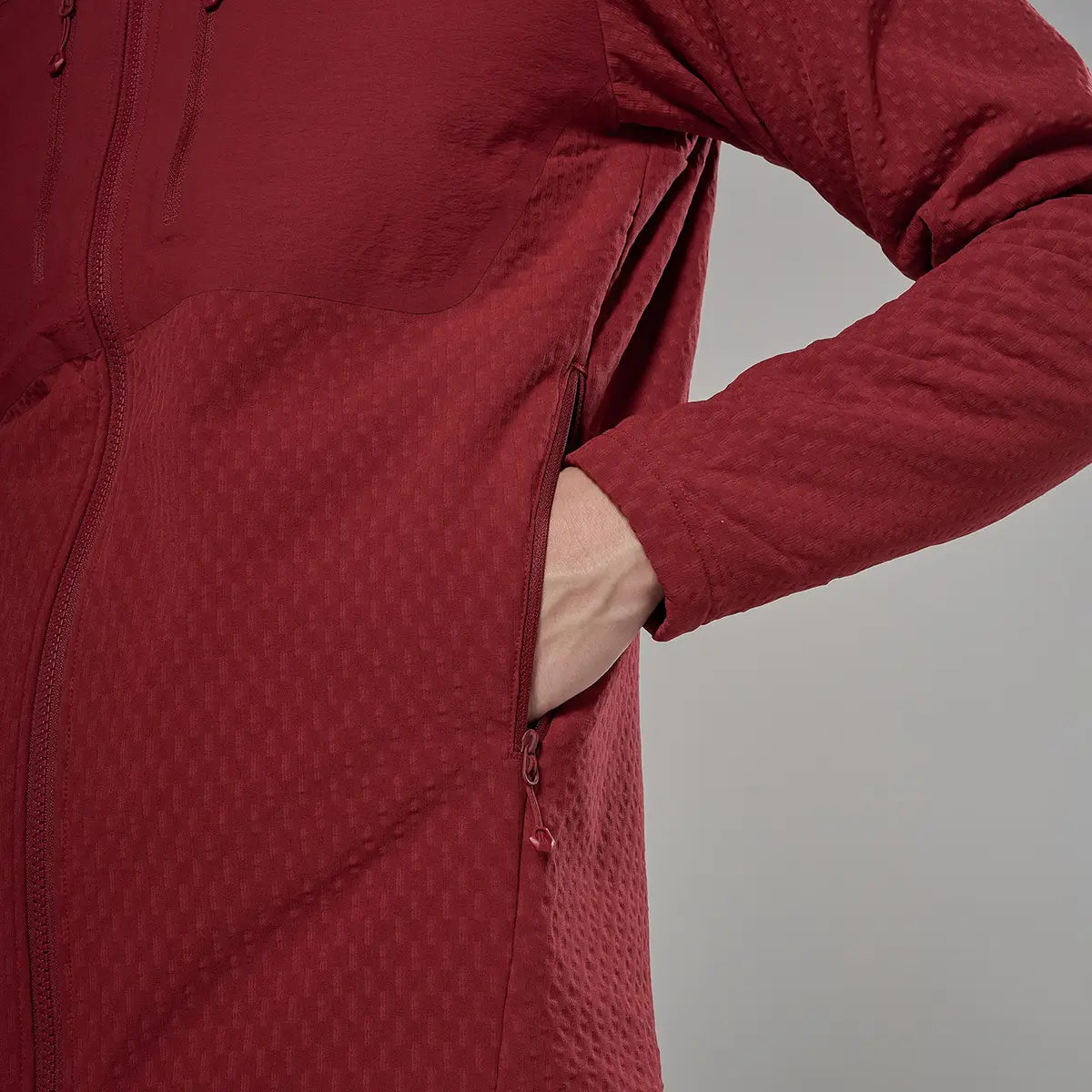 Side profile of male model in red Montane Mens Dura XT Hoodie fleece with hood, featuring textured fabric and functional pockets for active outdoor use