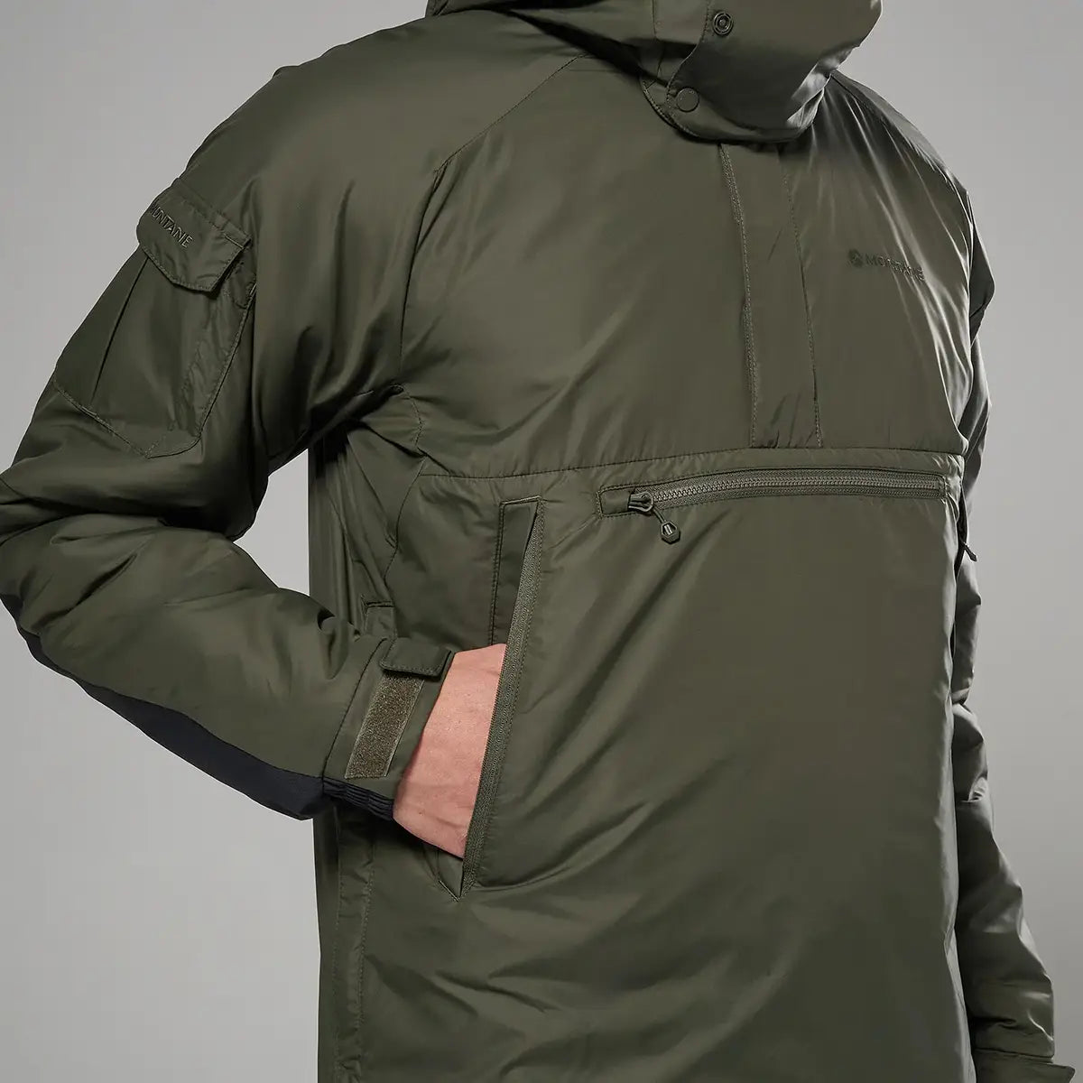 Montane Extreme Smock Insulated Mens jacket in olive with hand in front pocket, showcasing practical storage and warmth, John Bull Clothing.