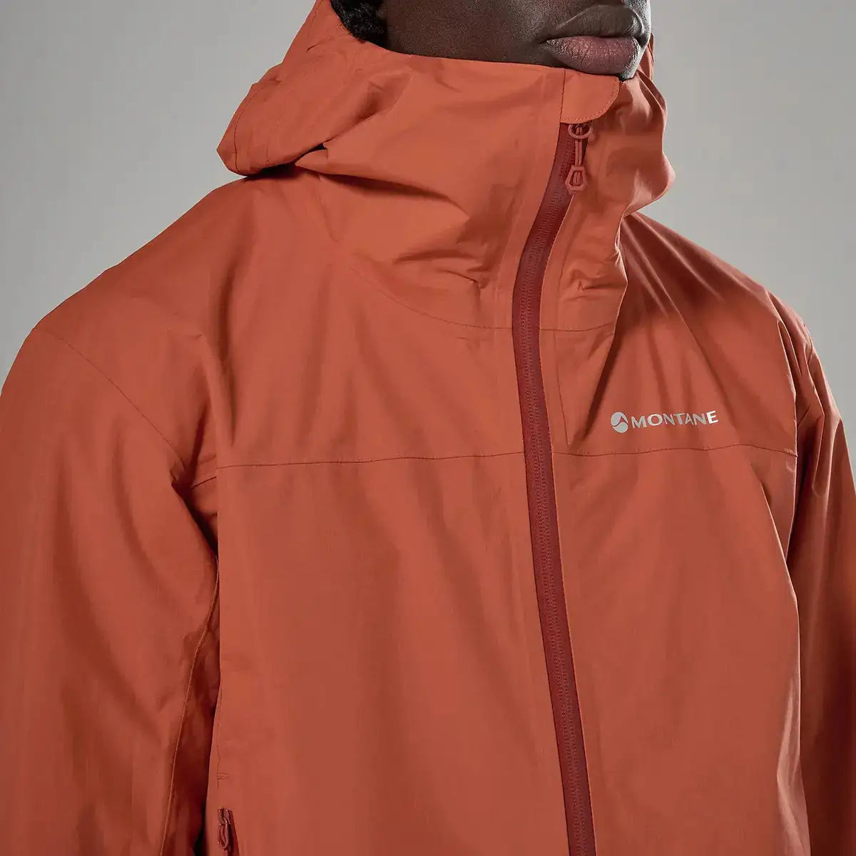 Close-up of orange Montane waterproof jacket with logo detail  from  John Bull Clothing 