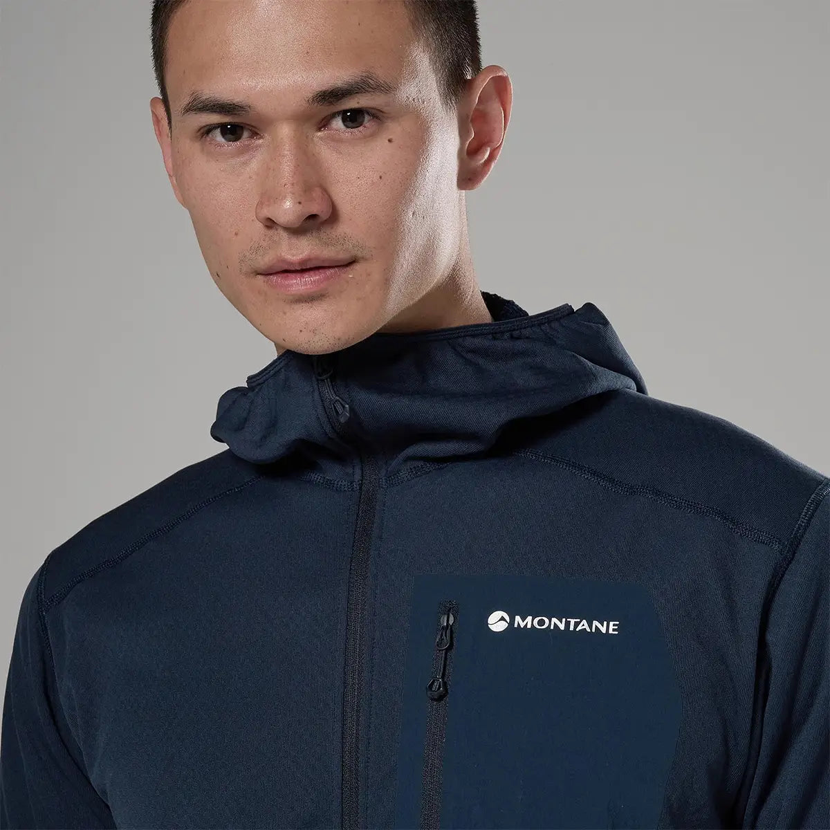 Male model wearing navy Montane Zepher Hooded Fleece Jacket with front zipper, logo on chest, and adjustable hood, designed for outdoor activities