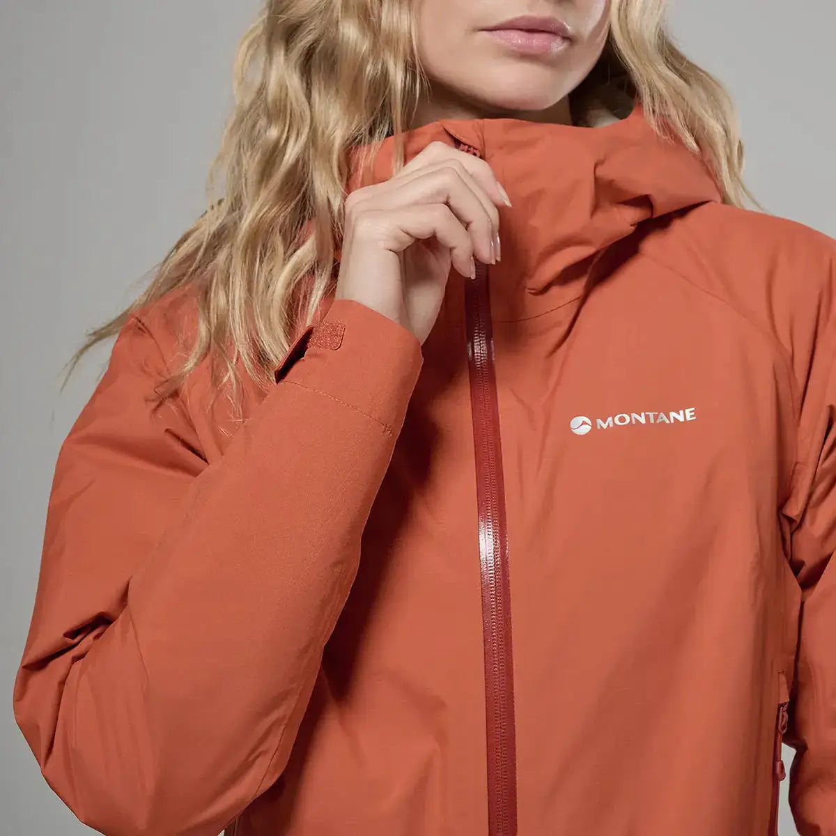 Close-up of Montane women's orange waterproof jacket with logo  from  John Bull Clothing 