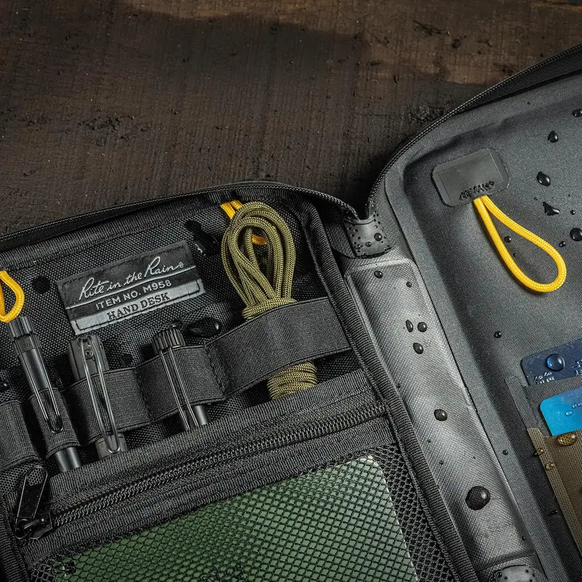 Open Rite in the Rain waterproof A5 desk holder with multiple storage pockets, elastic straps, and water-resistant fabric for outdoor organization