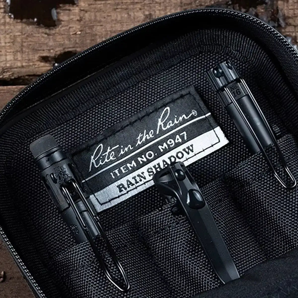 Black waterproof rain shadow pouch with zipper, inside a rugged black fabric organizer with label reading Rite in the Rain, ideal for outdoor essentials