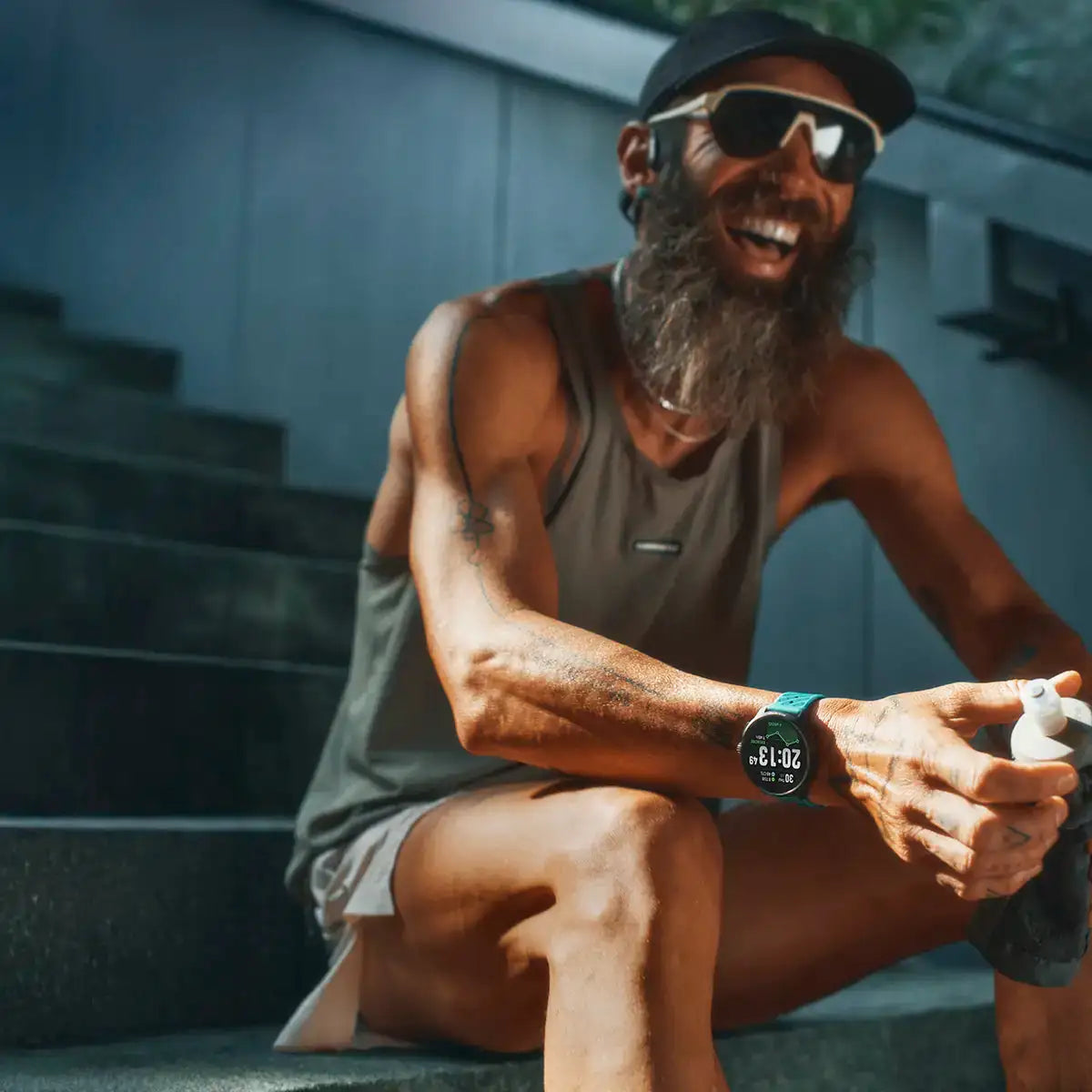 Male runner resting on stairs wearing Suunto Race 2 GPS Fitness Watch, emphasizing comfort and performance tracking.  from  John Bull Clothing 