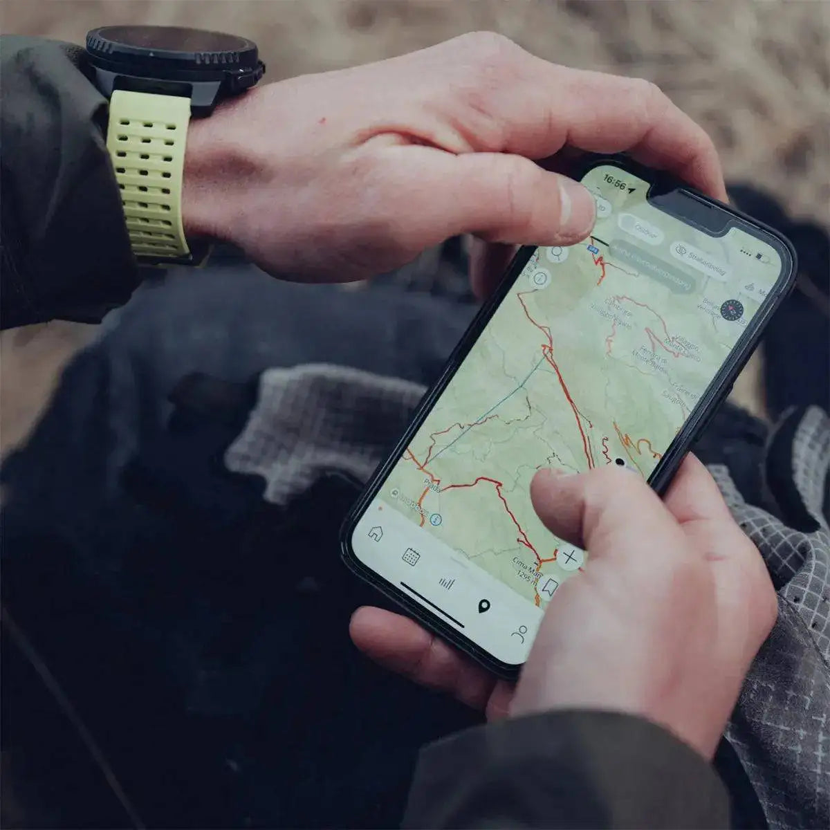 User navigating with the Suunto Vertical Solar GPS Smartwatch and smartphone, utilizing advanced mapping and GPS tracking for exploration.  from  John Bull Clothing 