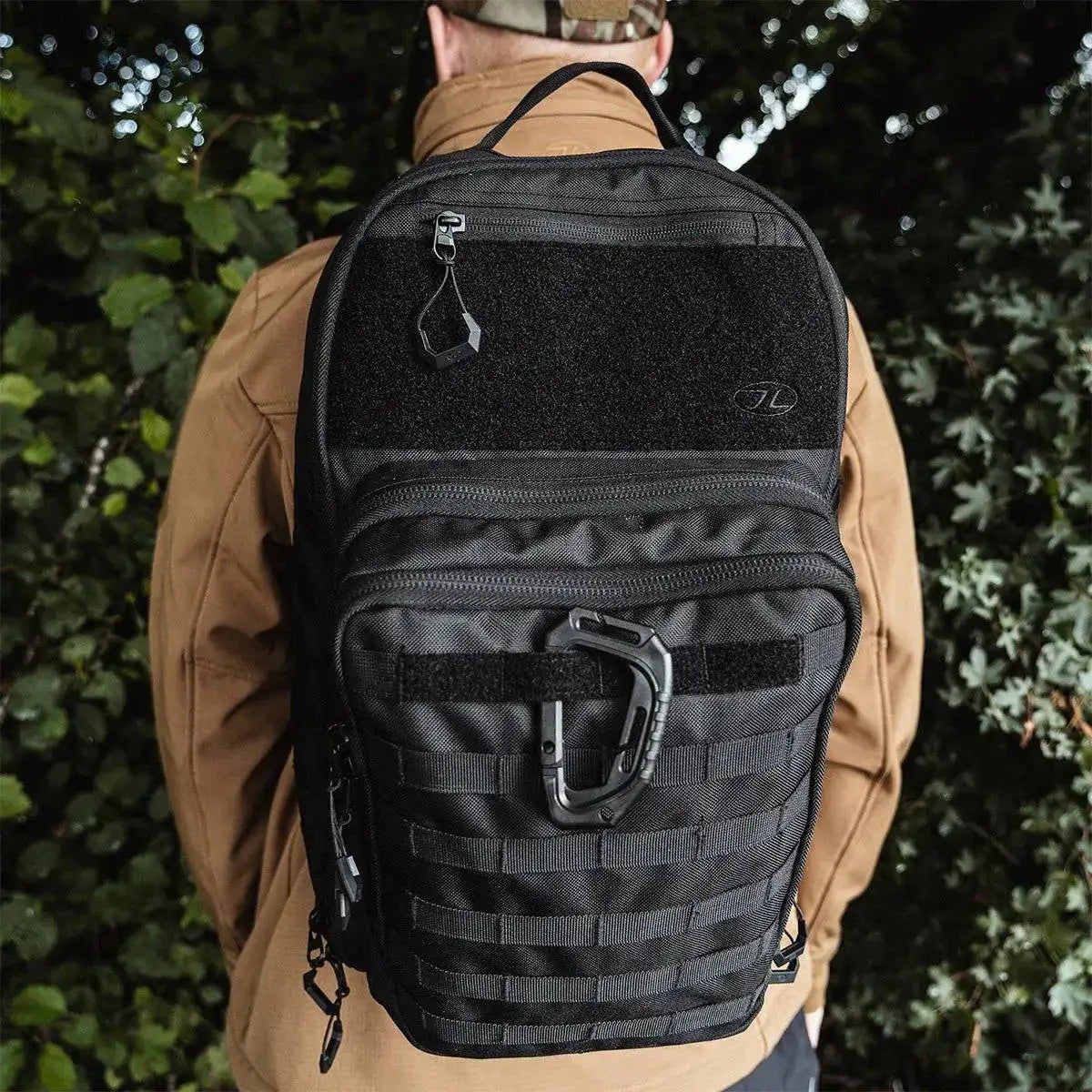Close-up of Highlander Harrier 25L Clamshell Rucksack in black worn by a person, showcasing MOLLE webbing and tactical utility for versatile use.  from  John Bull Clothing 