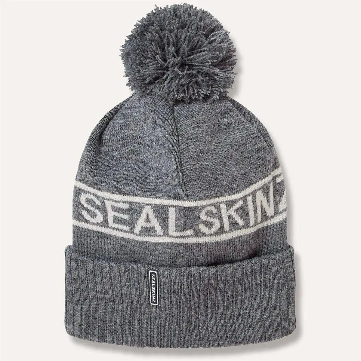 Grey Sealskinz Heacham Waterproof Cold Weather Icon Bobble Hat with white logo and pom-pom, perfect for cold, wet conditions. Dark Grey/Cream from  John Bull Clothing 