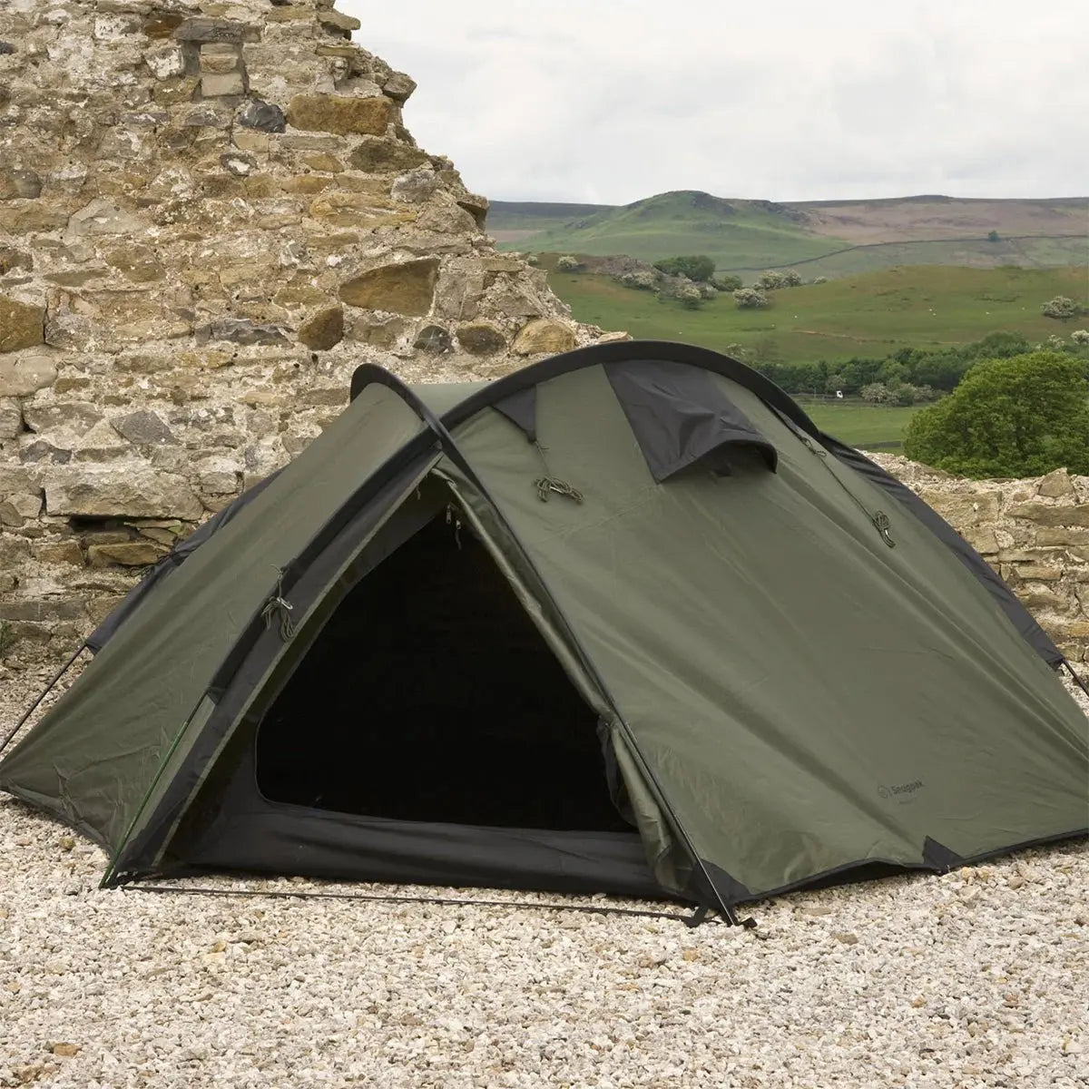 Snugpak The Bunker IX Expedition Tent in Olive set up on rocky terrain, featuring a durable, all-season design for extreme outdoor conditions.